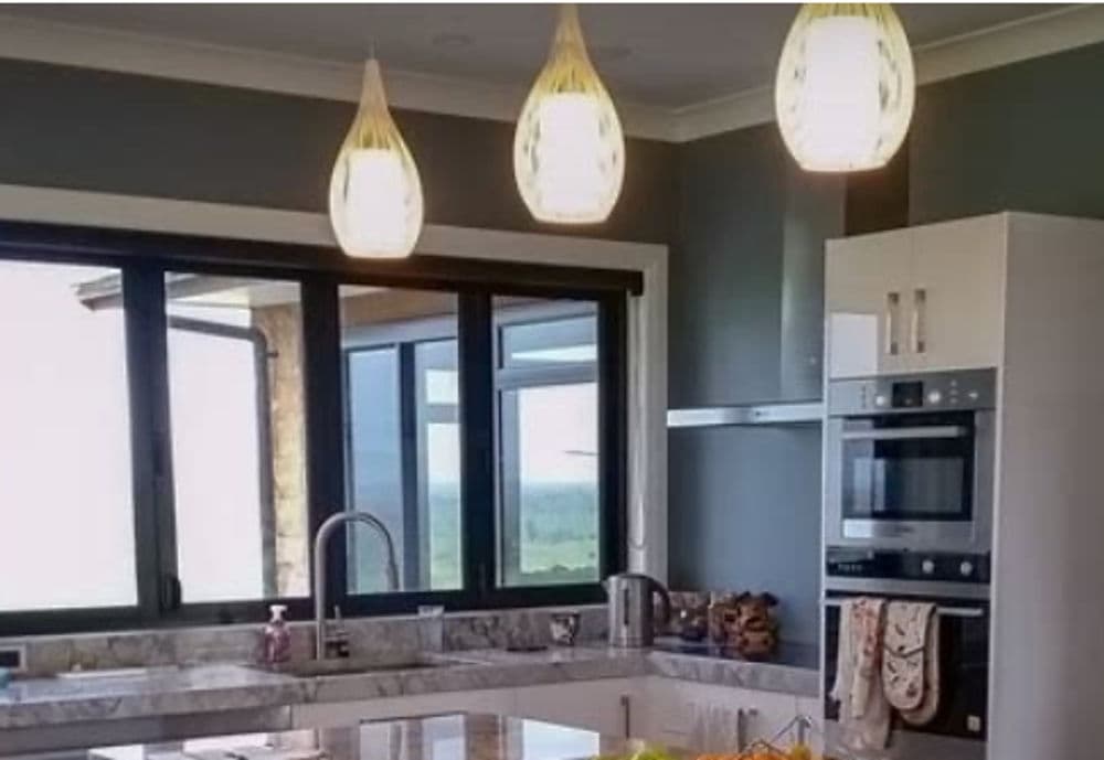 Modern kitchen with sleek white cabinetry, marble countertops, and stylish pendant lighting.