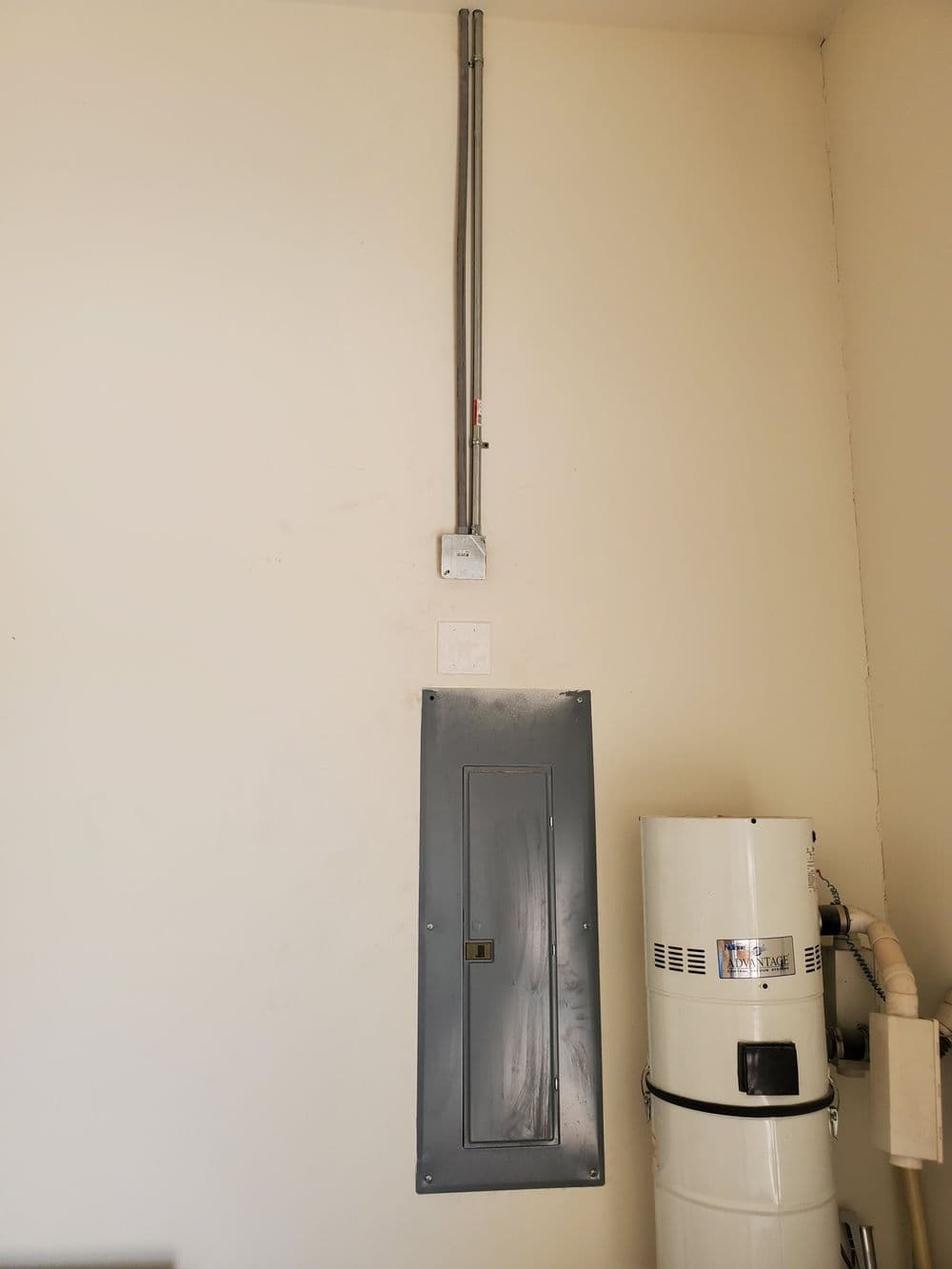 Electrical panel and water heater installed in a garage setting for residential use.