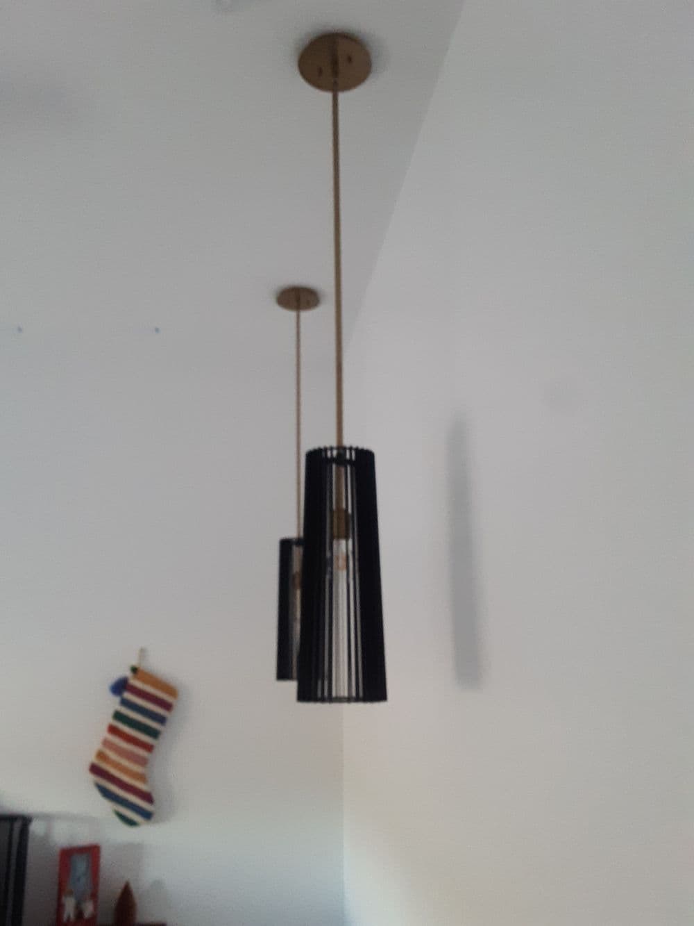 Modern black pendant lights hanging from a ceiling with a festive stocking in the background.
