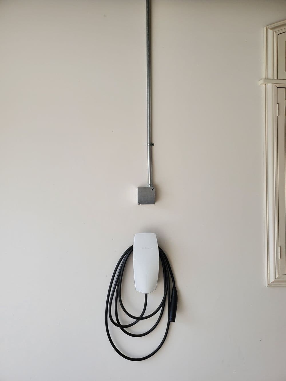 Wall-mounted electric vehicle charger with charging cable displayed neatly.