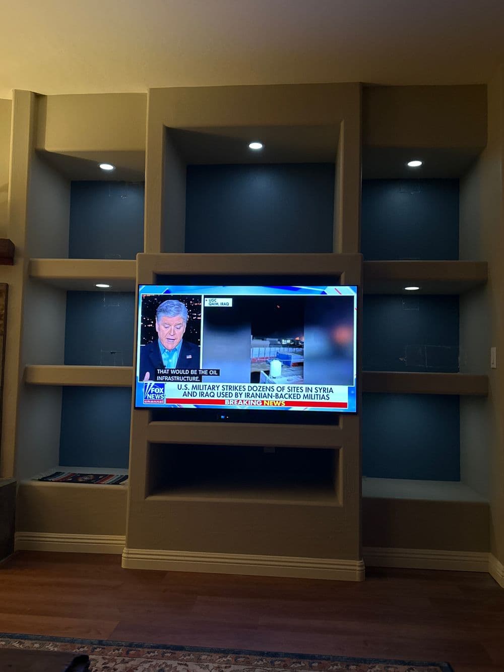 Television displaying news report on Syria airstrikes in a modern living room setting.