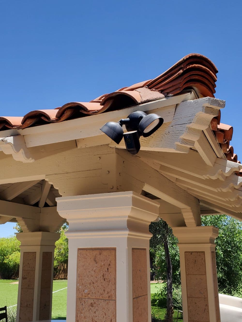 Exterior of a gazebo with decorative roof tiles and modern lighting fixture under clear blue sky.