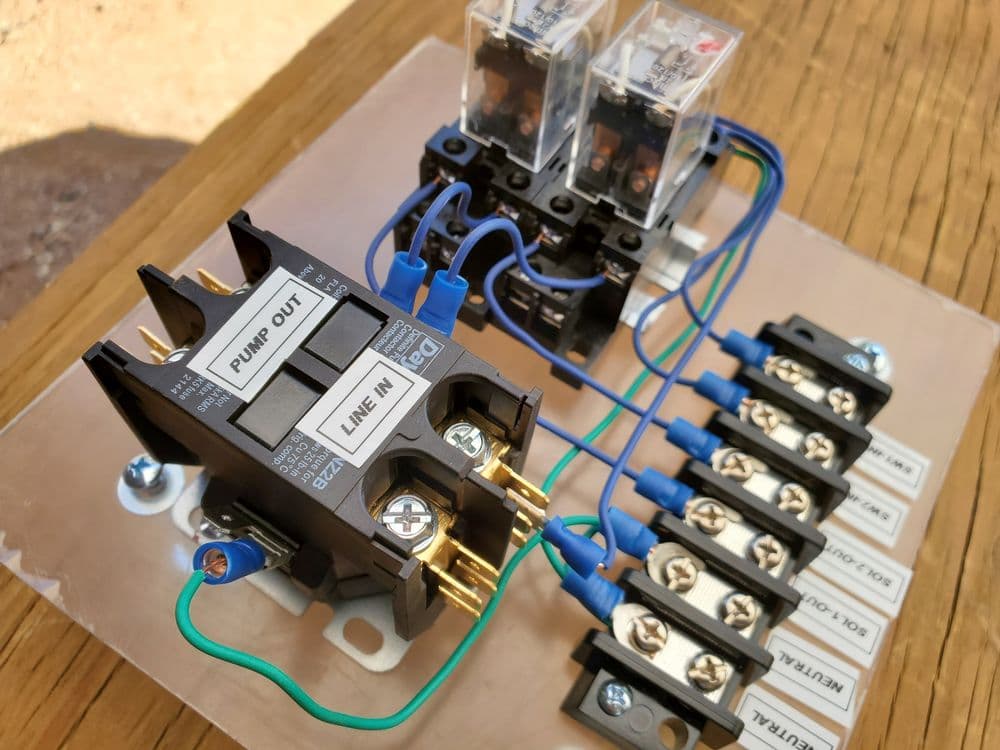 Electrical control panel with relays, terminal blocks, and wiring for pump operation.