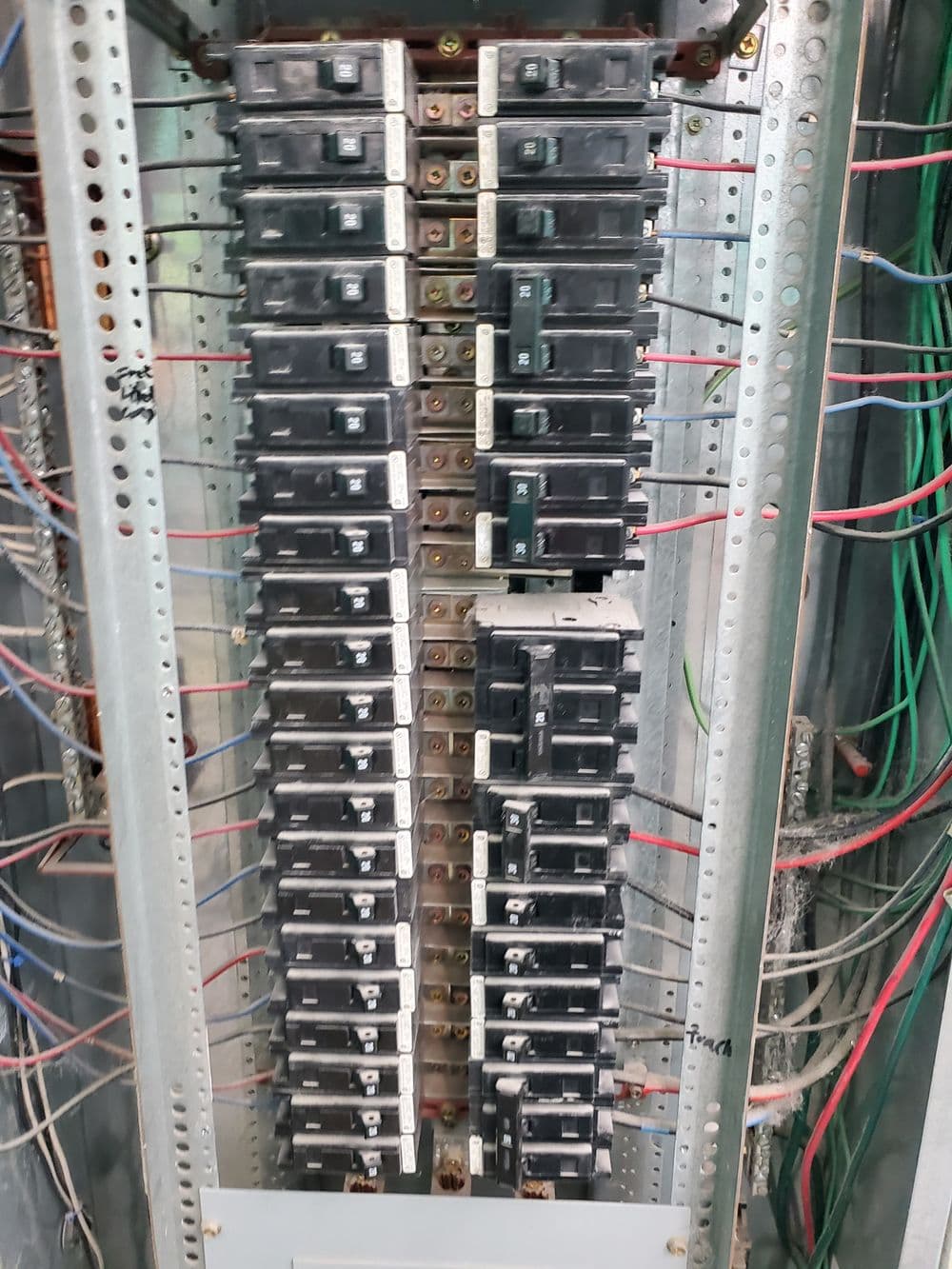 Electrical panel with circuit breakers and wiring, showcasing an organized power distribution system.